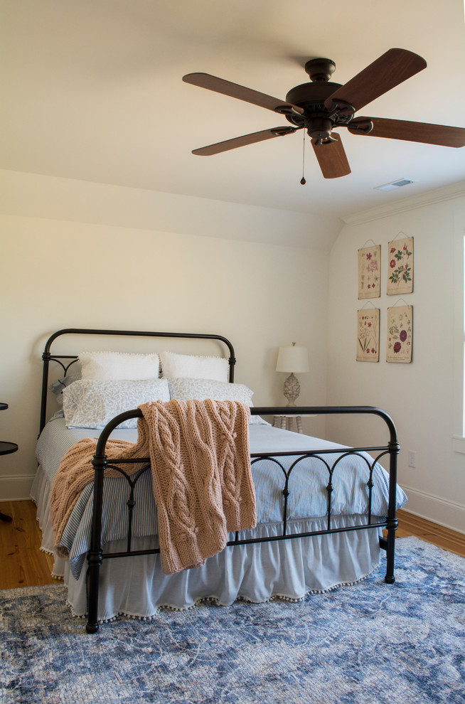 Photo of a medium sized farmhouse guest bedroom in Other with white walls, medium hardwood flooring and brown floors.