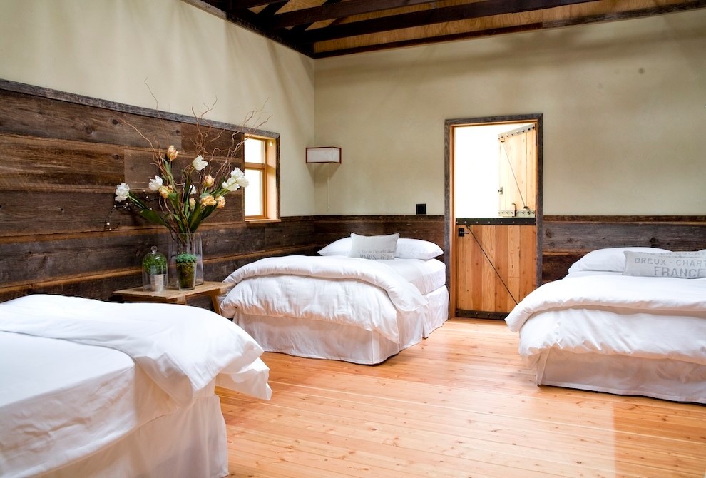 Ejemplo de habitación de invitados de estilo de casa de campo de tamaño medio con paredes beige y suelo de madera clara