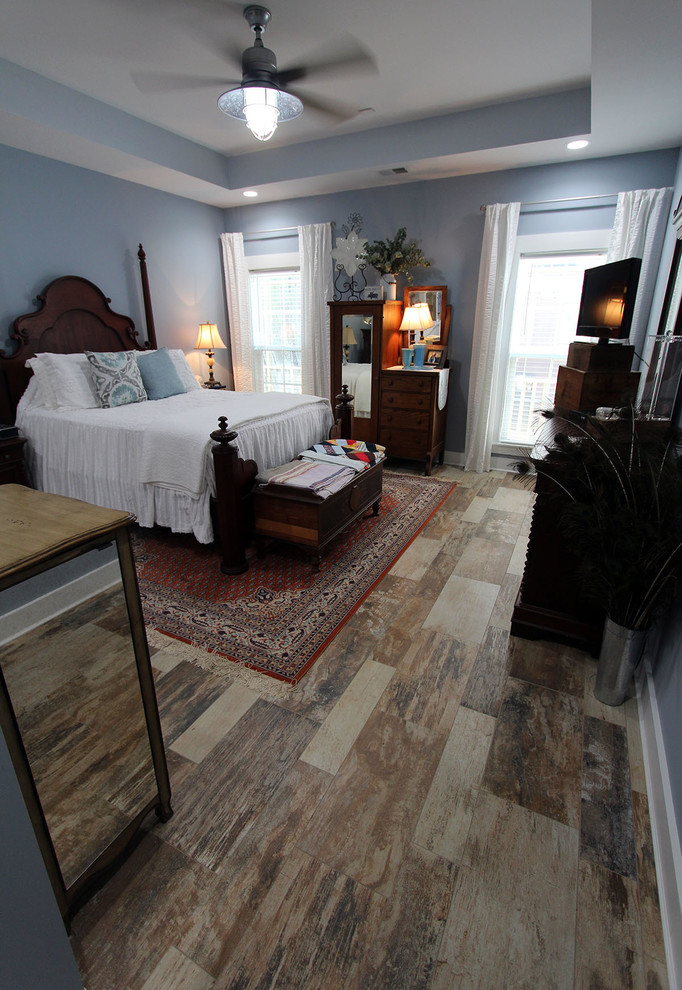 Modelo de dormitorio de estilo de casa de campo con paredes azules, suelo de baldosas de porcelana y suelo multicolor