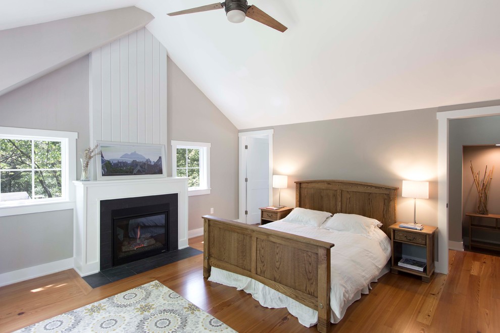 Imagen de dormitorio principal clásico grande con paredes grises, suelo de madera en tonos medios, todas las chimeneas y suelo marrón
