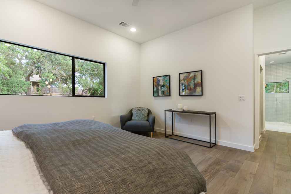 Mittelgroßes Modernes Gästezimmer ohne Kamin mit weißer Wandfarbe, braunem Holzboden und braunem Boden in Austin