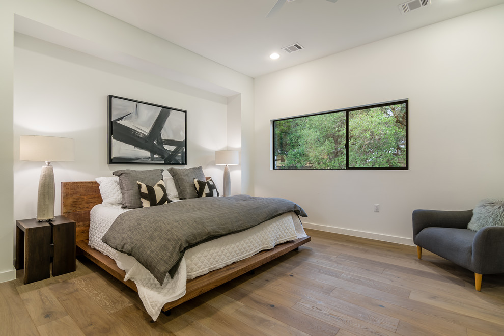 Diseño de habitación de invitados contemporánea de tamaño medio sin chimenea con paredes blancas, suelo de madera en tonos medios y suelo marrón