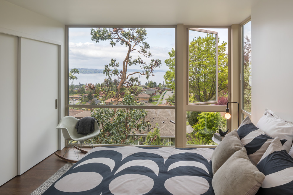 Modernes Schlafzimmer mit weißer Wandfarbe, dunklem Holzboden und braunem Boden in Seattle