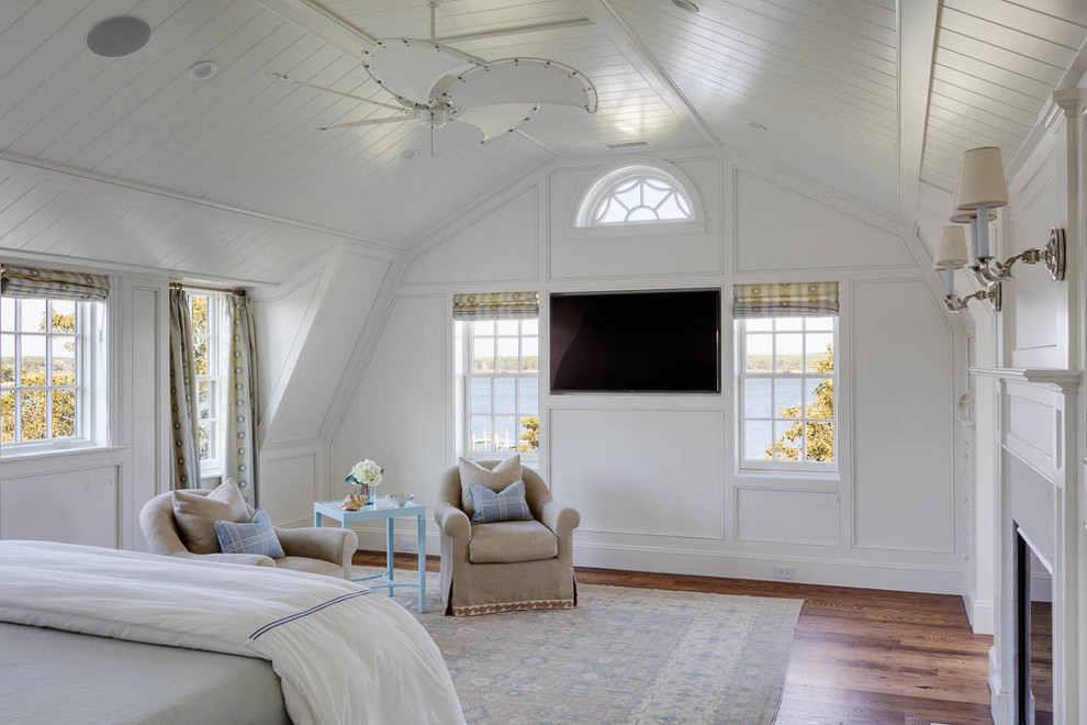 Ejemplo de dormitorio principal marinero de tamaño medio con paredes blancas, suelo de madera en tonos medios, todas las chimeneas y marco de chimenea de yeso