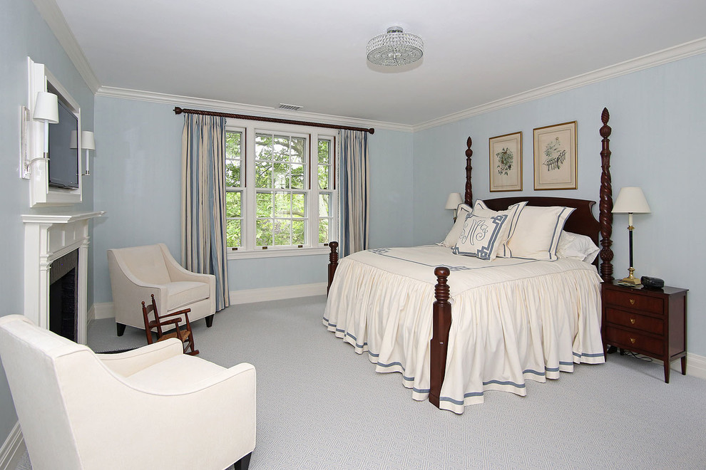 На фото: хозяйская спальня в классическом стиле с синими стенами, ковровым покрытием, стандартным камином и фасадом камина из дерева