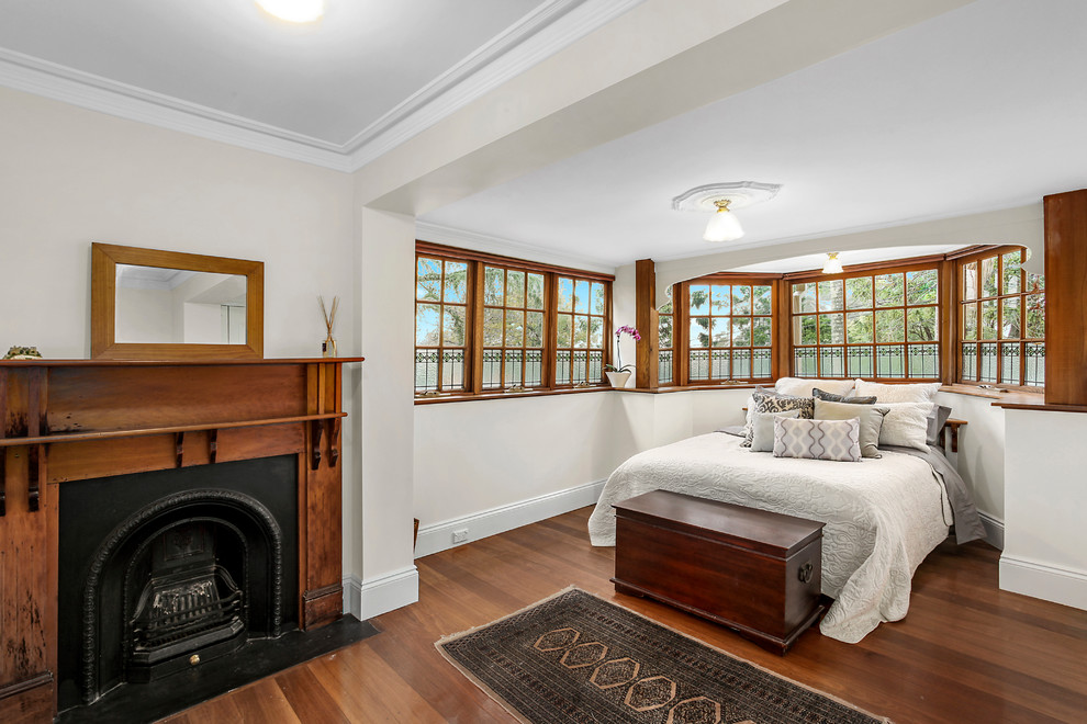 Klassisches Gästezimmer mit weißer Wandfarbe, braunem Holzboden und Kamin in Sydney