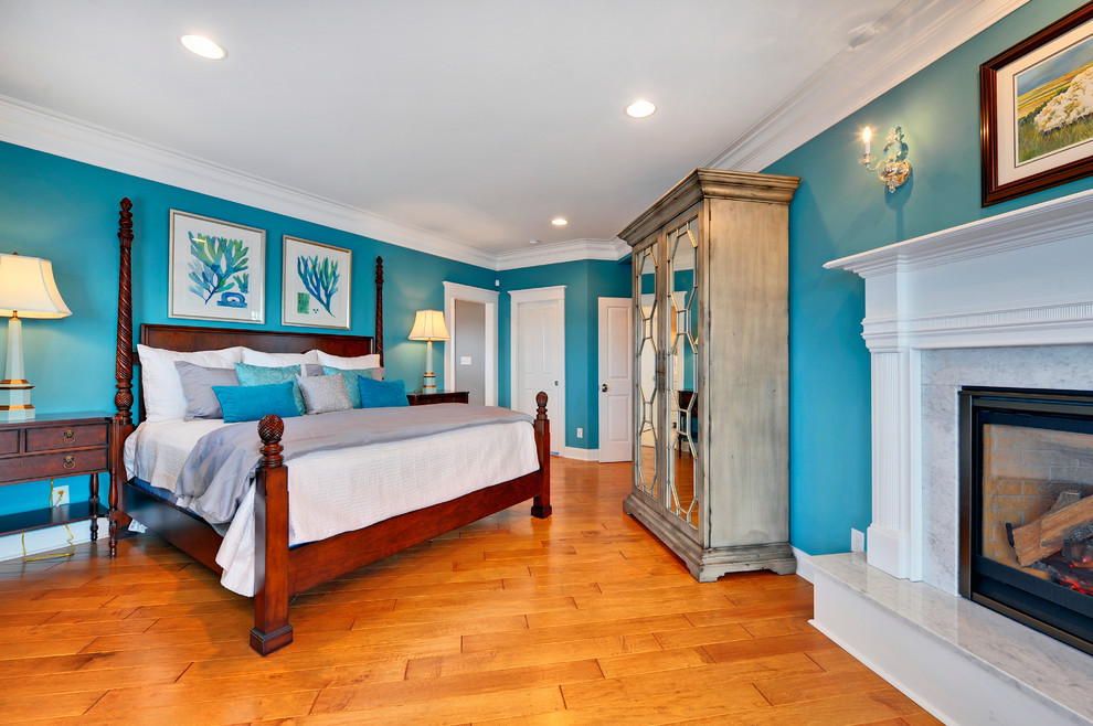 Foto på ett maritimt sovrum, med blå väggar, mellanmörkt trägolv och en standard öppen spis