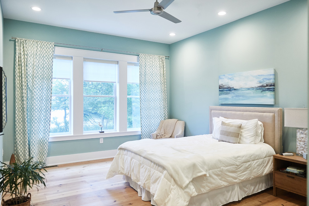 Ejemplo de habitación de invitados costera sin chimenea con paredes azules, suelo de madera clara y suelo beige