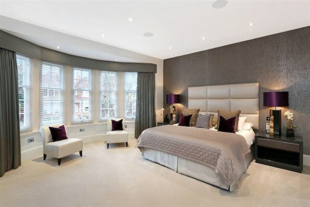 Expansive contemporary master bedroom in London with beige walls, carpet, no fireplace and white floors.