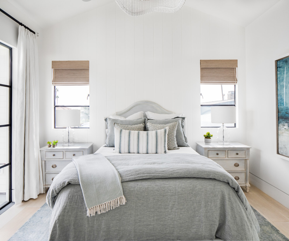 Beach style guest bedroom in Orange County with white walls, light hardwood flooring and no fireplace.
