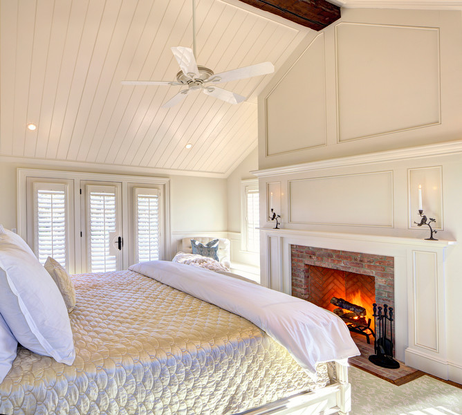 Ejemplo de dormitorio principal clásico grande con paredes blancas, suelo de madera en tonos medios, todas las chimeneas y marco de chimenea de ladrillo