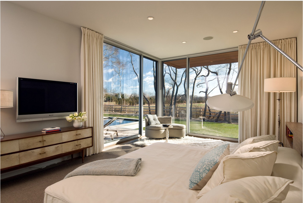 Ejemplo de dormitorio principal y televisión minimalista con paredes beige y moqueta