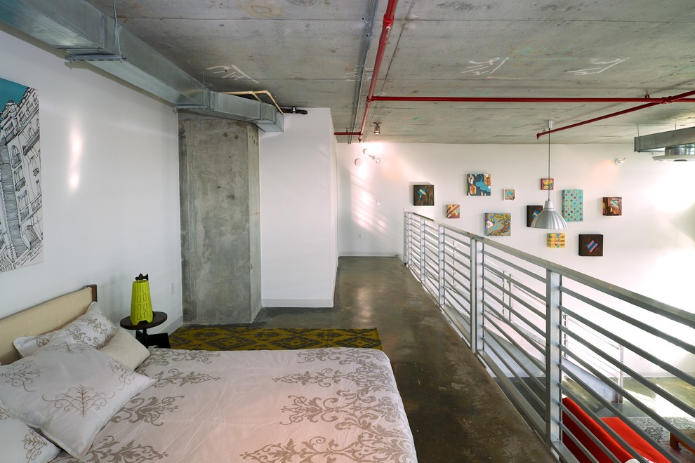 Industriell inredning av ett sovloft, med vita väggar och betonggolv