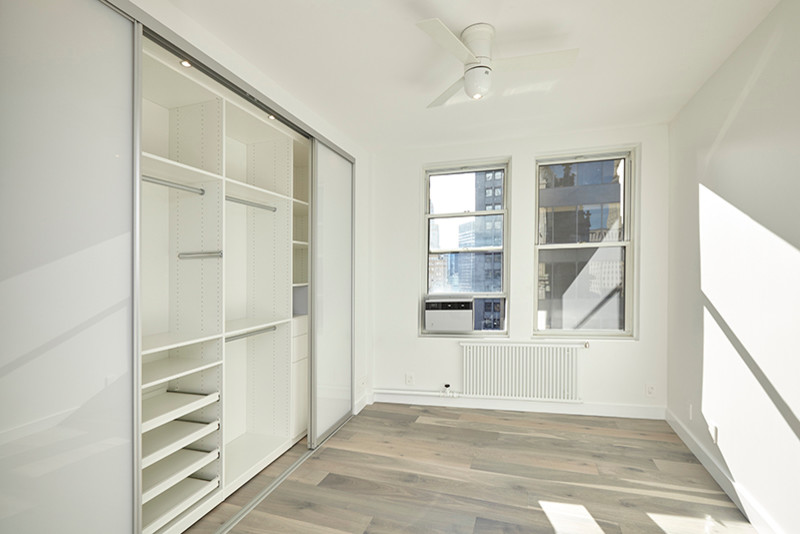 Cette image montre une chambre parentale design de taille moyenne avec un mur blanc, parquet clair, aucune cheminée et un sol gris.