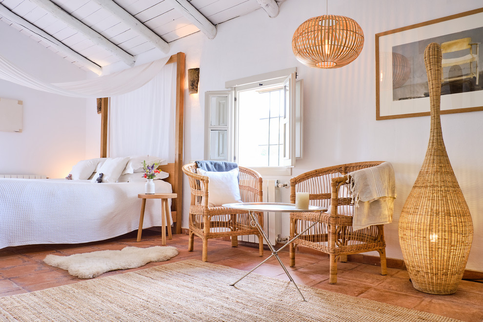 Diseño de dormitorio campestre con paredes blancas, suelo de baldosas de terracota y suelo marrón