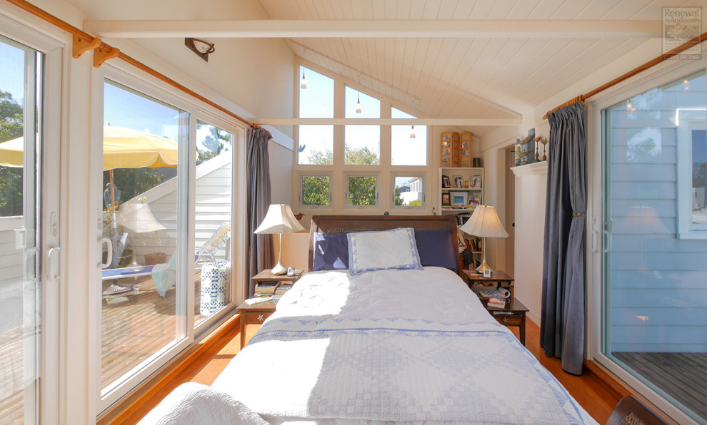 Immagine di una camera da letto stile loft di medie dimensioni con pareti bianche, pavimento in legno massello medio, stufa a legna, pavimento marrone e travi a vista