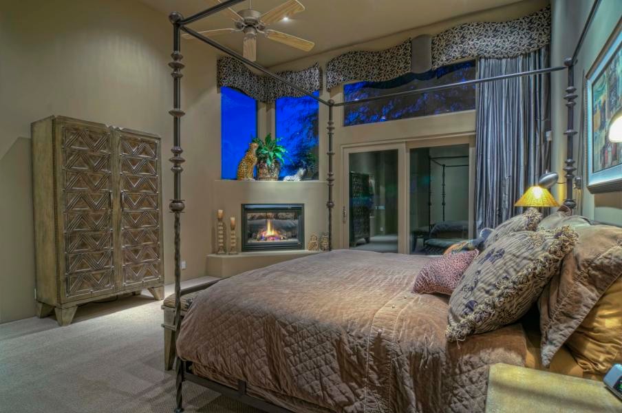 This is an example of an expansive classic master bedroom in Phoenix with beige walls, carpet, a standard fireplace and a stone fireplace surround.