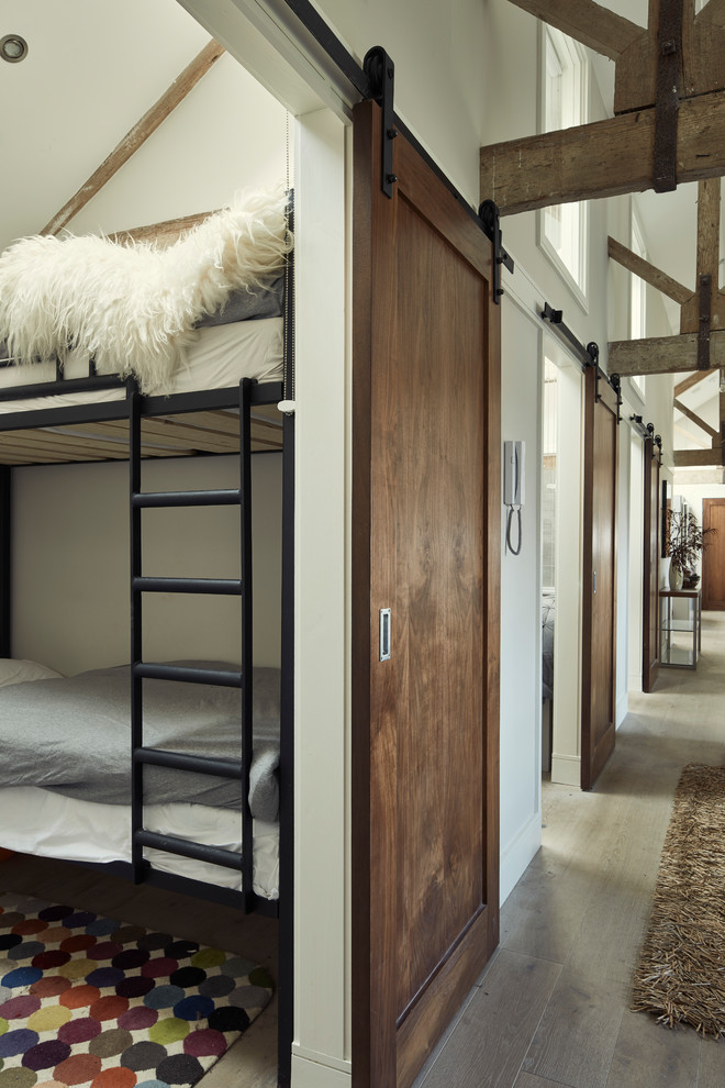 他の地域にある小さなインダストリアルスタイルのおしゃれな客用寝室 (白い壁、無垢フローリング、茶色い床) のインテリア