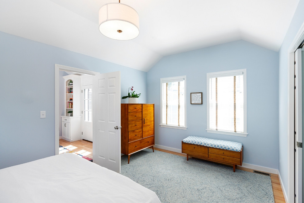 Modelo de dormitorio principal tradicional renovado grande con paredes azules y suelo de madera clara