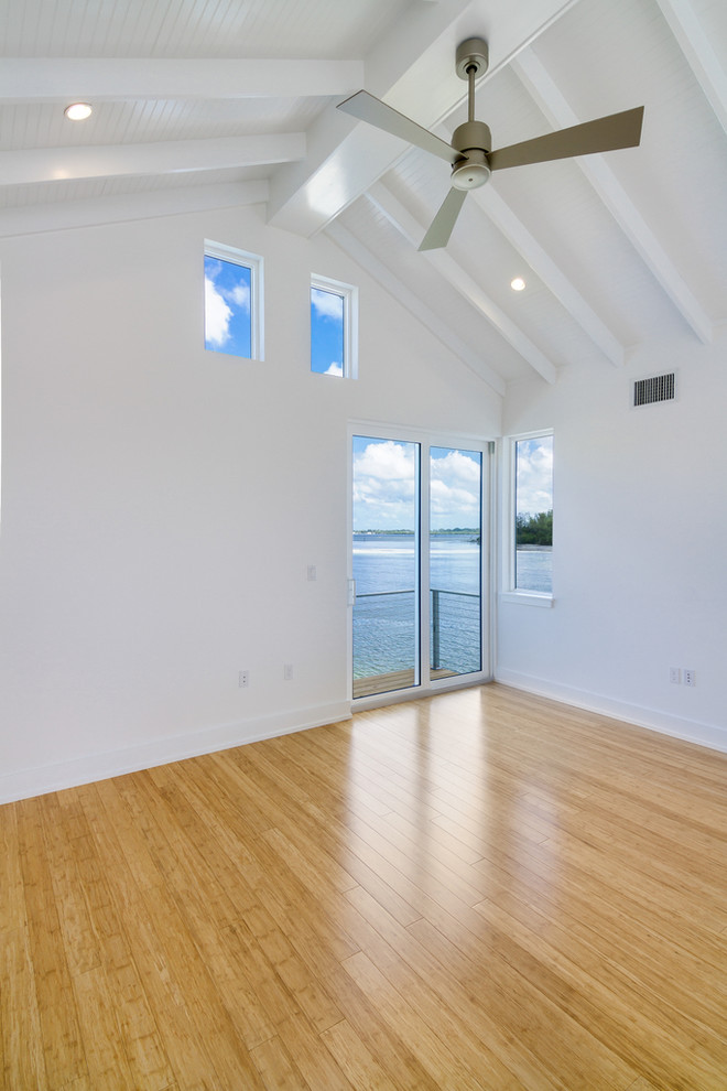 Immagine di una camera degli ospiti minimal di medie dimensioni con pareti bianche, pavimento in bambù e nessun camino