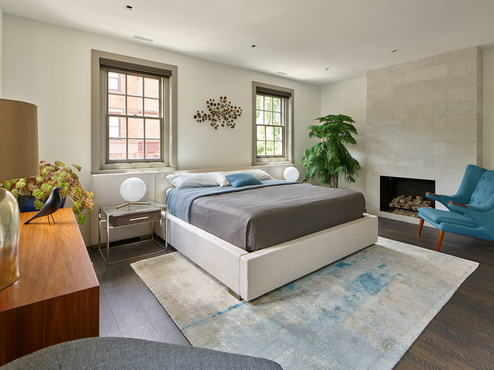 Inredning av ett modernt sovrum, med vita väggar, mörkt trägolv, en standard öppen spis, en spiselkrans i trä och brunt golv