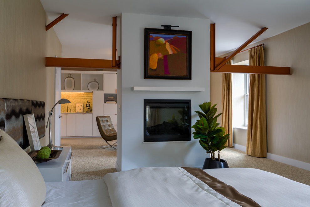 На фото: большая хозяйская спальня в стиле неоклассика (современная классика) с ковровым покрытием и двусторонним камином