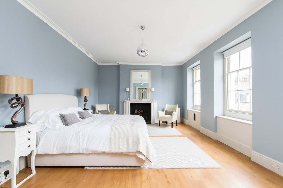 Traditional grey and silver bedroom in London with blue walls and medium hardwood flooring.