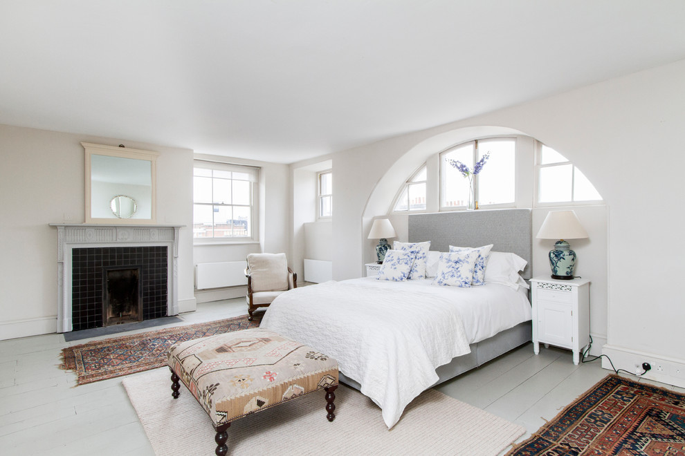 Eklektisches Schlafzimmer mit weißer Wandfarbe, gebeiztem Holzboden, Kamin und gefliester Kaminumrandung in London