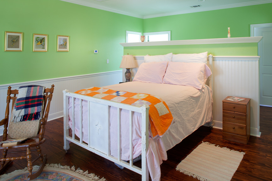 Imagen de dormitorio principal campestre de tamaño medio sin chimenea con paredes verdes y suelo de madera en tonos medios