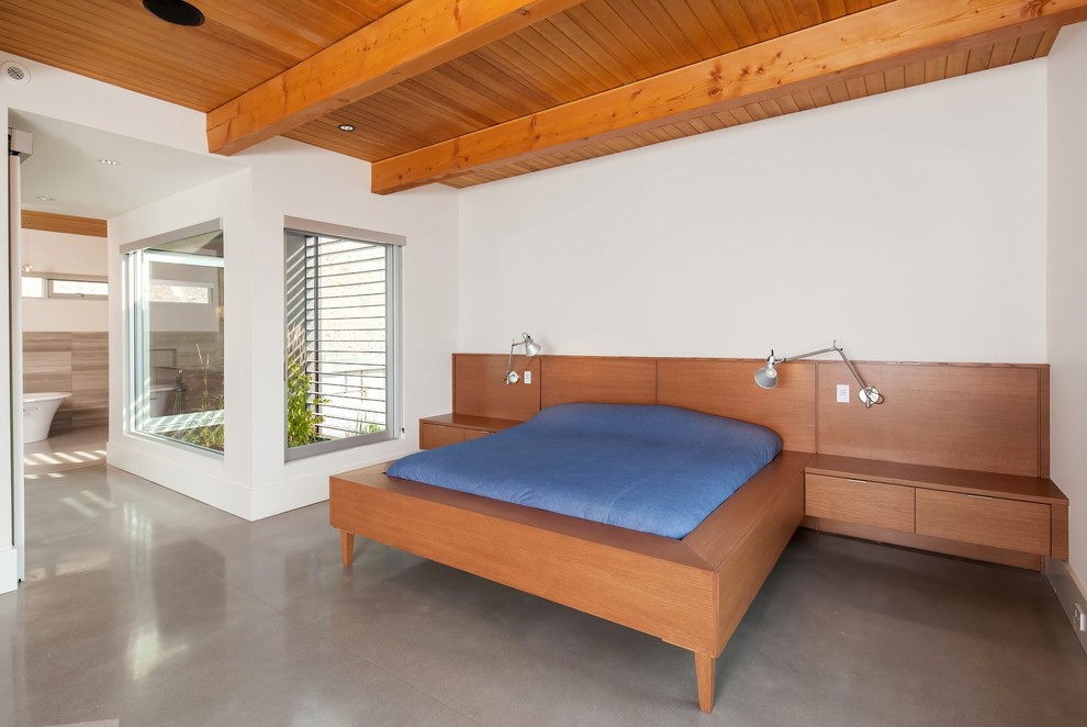 Immagine di una camera degli ospiti minimal di medie dimensioni con pareti bianche e pavimento in cemento