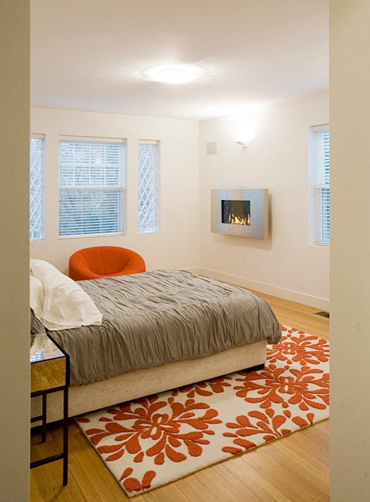 Foto de dormitorio principal actual de tamaño medio con paredes blancas, suelo de madera clara, todas las chimeneas y marco de chimenea de metal