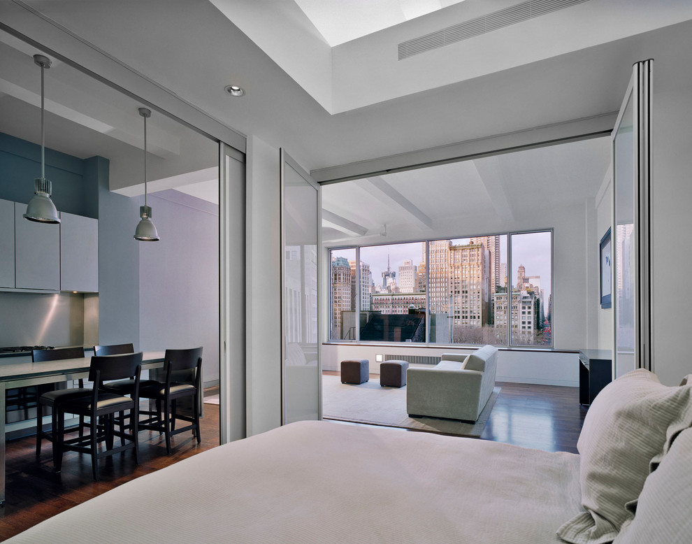 Immagine di una camera da letto stile loft moderna di medie dimensioni con pareti bianche, parquet scuro e pavimento marrone