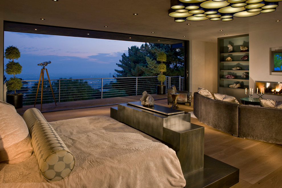 На фото: большая хозяйская спальня в современном стиле с коричневыми стенами, светлым паркетным полом и горизонтальным камином с