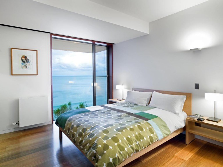 Ejemplo de habitación de invitados actual de tamaño medio sin chimenea con paredes blancas y suelo de madera en tonos medios