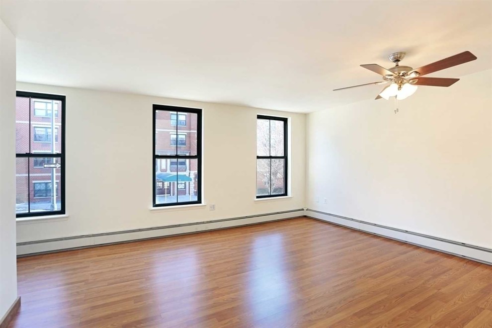 Mittelgroßes Uriges Hauptschlafzimmer mit weißer Wandfarbe, hellem Holzboden und rotem Boden in New York