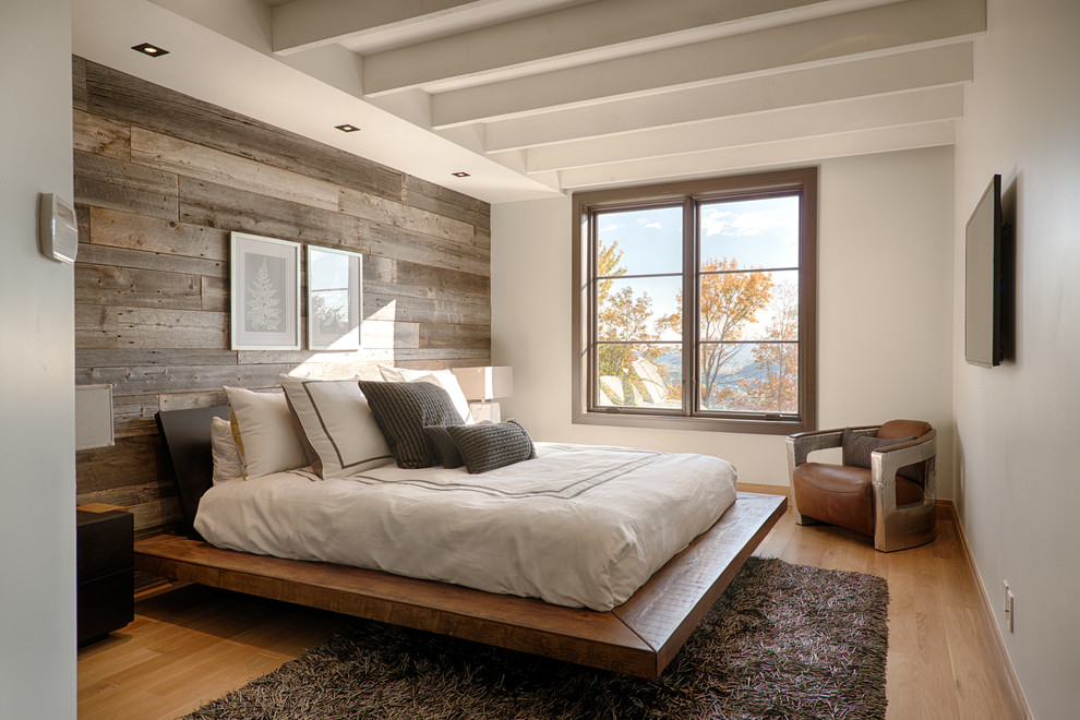 Modelo de dormitorio televisión rústico con paredes blancas y suelo de madera en tonos medios