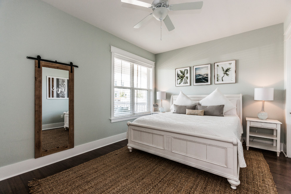 Modelo de habitación de invitados marinera grande con paredes verdes, suelo de madera en tonos medios y suelo marrón