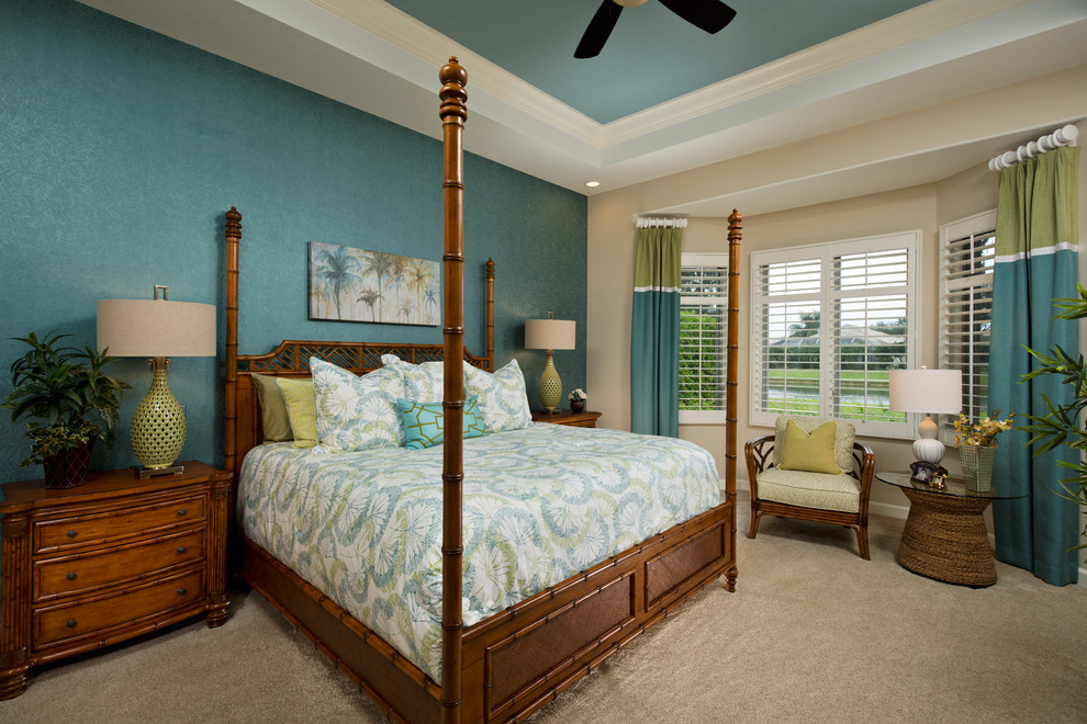 Modelo de dormitorio tropical de tamaño medio con paredes azules, moqueta y suelo beige