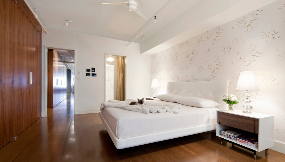Modelo de dormitorio principal actual grande sin chimenea con paredes multicolor, suelo de madera en tonos medios y suelo marrón