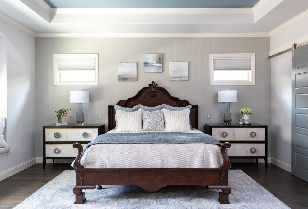 Transitional dark wood floor, brown floor, tray ceiling and wallpaper bedroom photo in Dallas with gray walls
