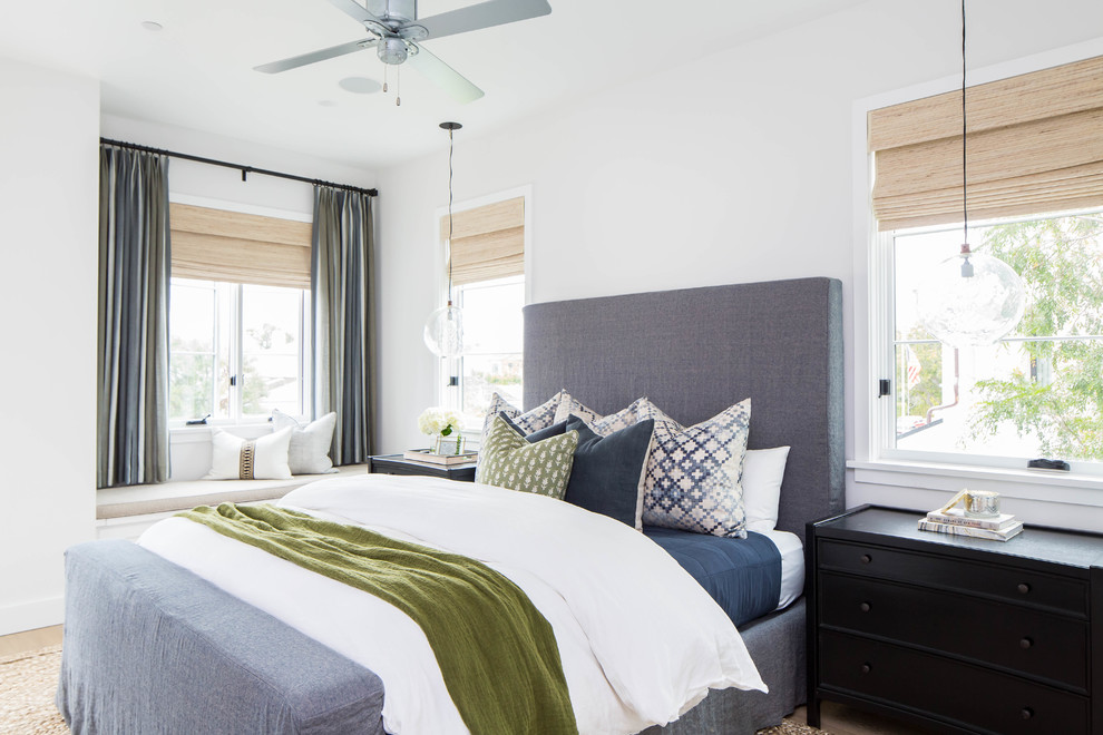Mittelgroßes Maritimes Hauptschlafzimmer mit weißer Wandfarbe, braunem Holzboden, Kamin, Kaminumrandung aus Backstein und beigem Boden in Orange County