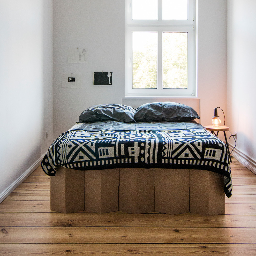 Immagine di una piccola camera da letto contemporanea con pareti bianche, pavimento in legno massello medio e nessun camino