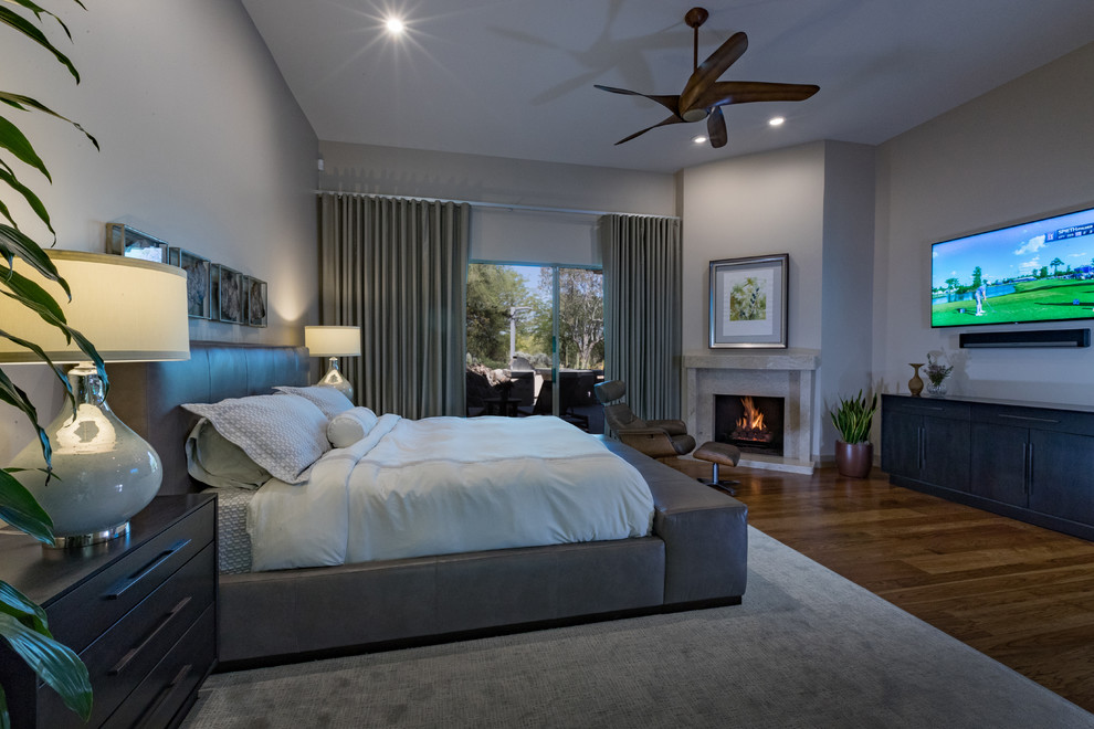 フェニックスにある広いコンテンポラリースタイルのおしゃれな主寝室 (グレーの壁、無垢フローリング、コーナー設置型暖炉、石材の暖炉まわり、茶色い床)
