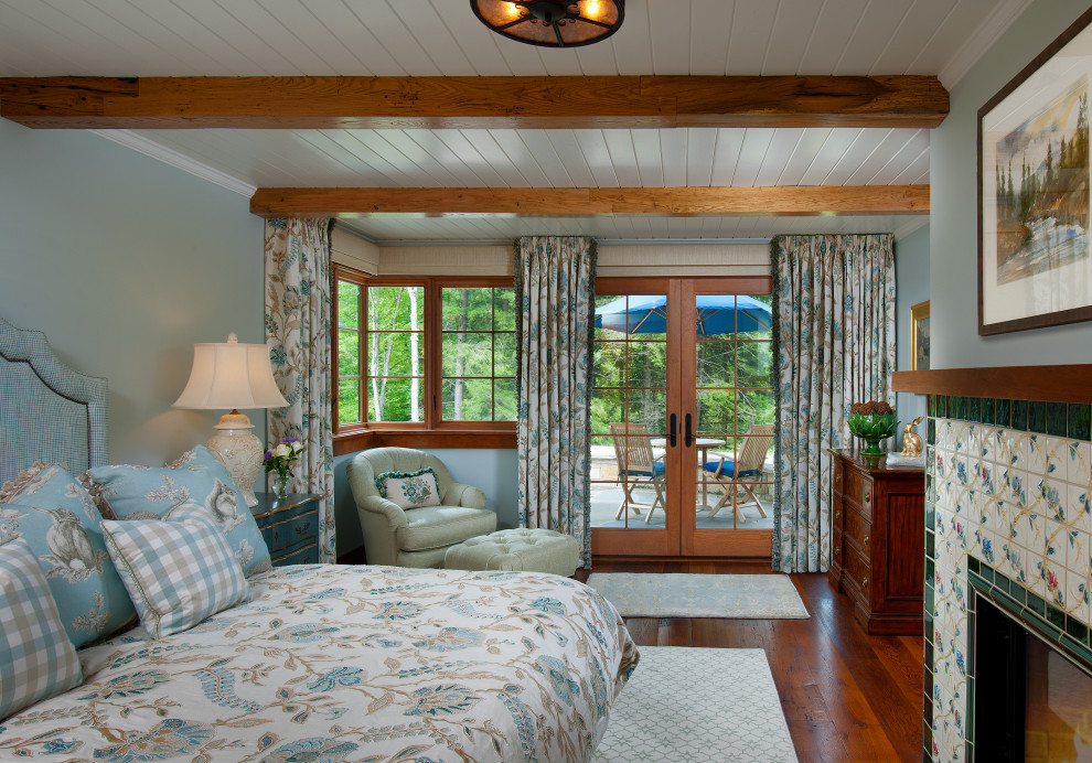 Inspiration pour une chambre parentale traditionnelle de taille moyenne avec un mur bleu, un sol en bois brun, une cheminée standard et un manteau de cheminée en carrelage.