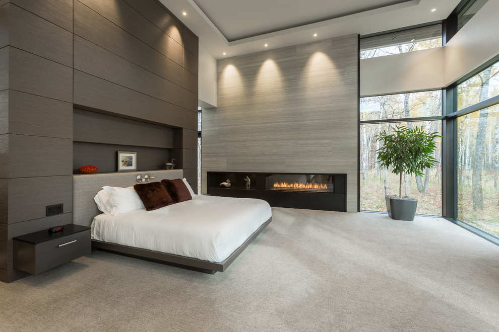 Modelo de dormitorio principal actual con paredes grises, moqueta, chimenea lineal y suelo gris
