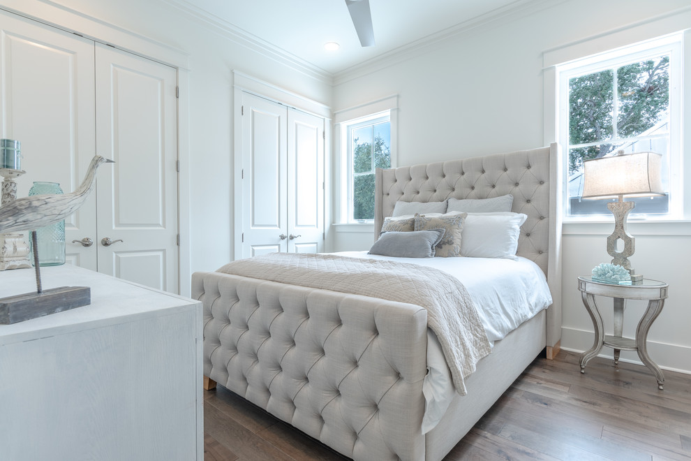 Ejemplo de habitación de invitados marinera de tamaño medio sin chimenea con paredes blancas, suelo de madera clara y suelo marrón