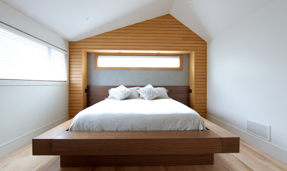 Photo of a large contemporary master bedroom in Vancouver with white walls and light hardwood flooring.