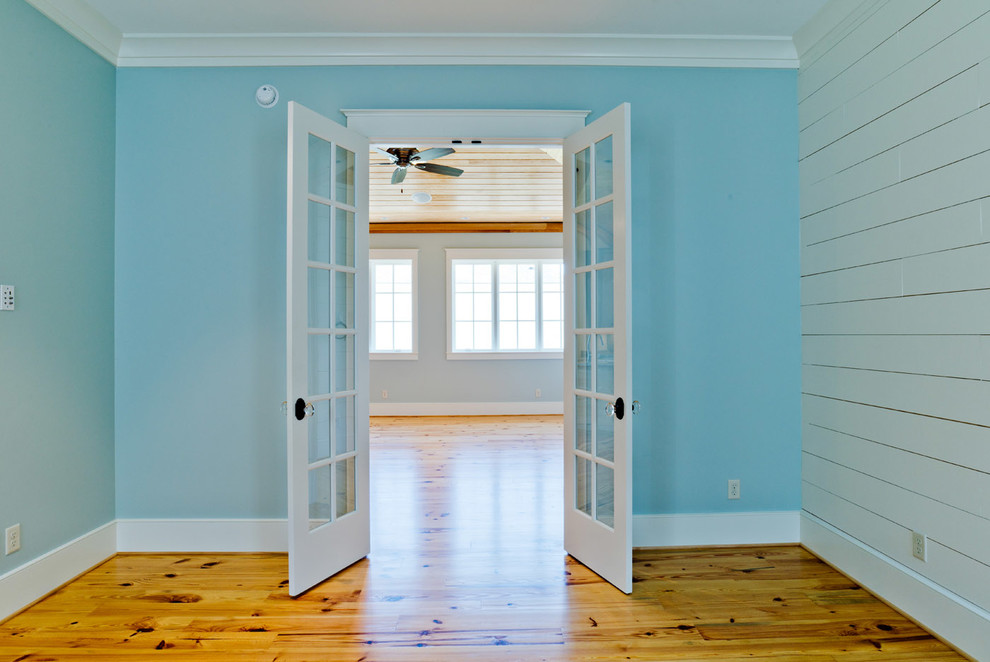 Foto di una camera matrimoniale stile marinaro di medie dimensioni con pareti blu, pavimento in legno massello medio e nessun camino