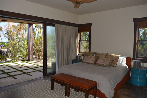 Diseño de habitación de invitados costera grande sin chimenea con paredes beige, suelo de madera oscura y suelo marrón