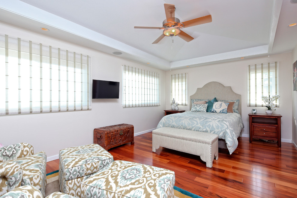 This is an example of a world-inspired master bedroom in Hawaii with beige walls and medium hardwood flooring.